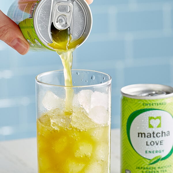 A hand pouring Ito En Matcha Love Sweetened Matcha Green Tea from a green bottle into a glass with ice.