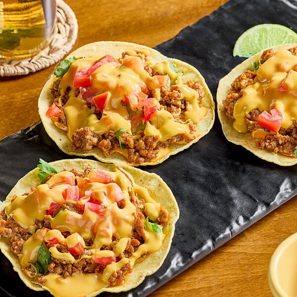 A plate of three tacos with meat and Chef-Mate Jalapeno Cheddar Cheese Sauce on top.