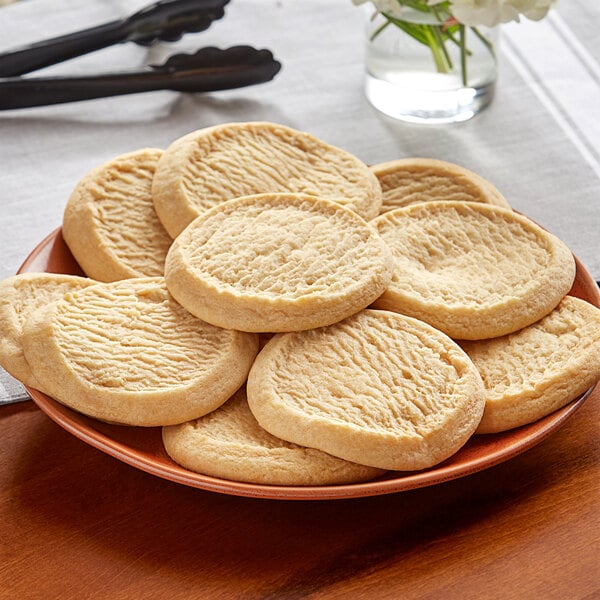 A plate of Otis Spunkmeyer sugar cookies on a table.