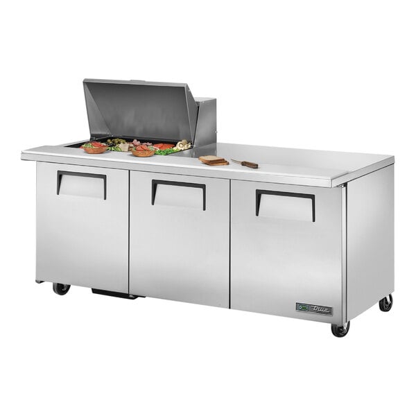 A True 3 door stainless steel commercial sandwich prep table with food on it.