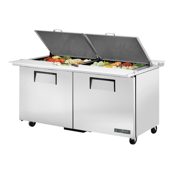 A True stainless steel 2 door refrigerated sandwich prep table with food on the counter.