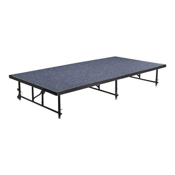 A National Public Seating blue carpet stage platform with black legs and wheels.