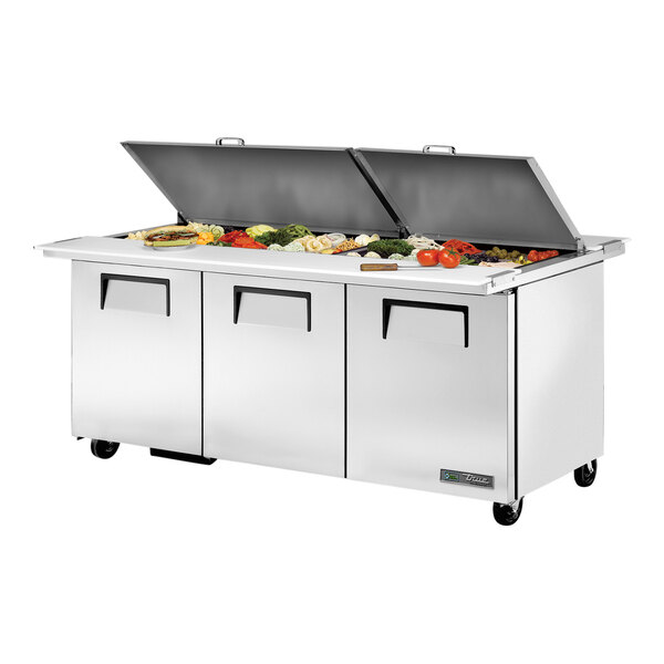 A True 72 3/8" refrigerated sandwich prep table with food on top.