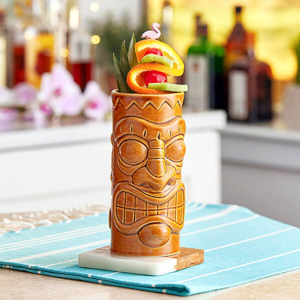 An Acopa brown ceramic tiki mug with fruit on top on a white surface.