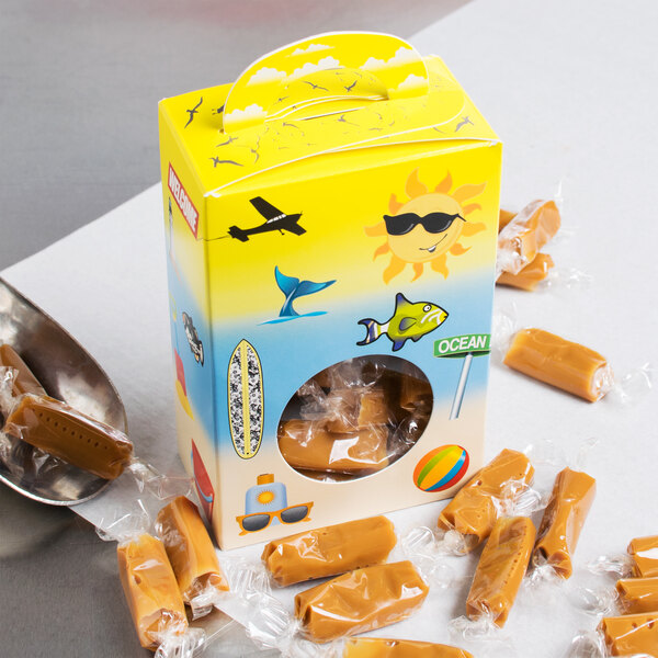 A yellow Beach Window Candy Box filled with caramel candies on a table.