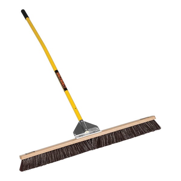 A Structron general purpose push broom with a yellow handle.