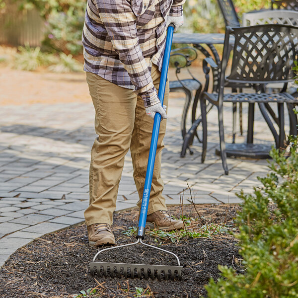 A person using a Seymour rake with a blue fiberglass handle.