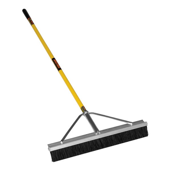 A Structron commercial push broom with a yellow handle.