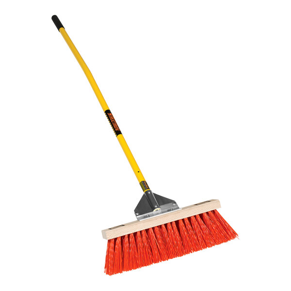 A Structron street/landscape push broom with a yellow handle.