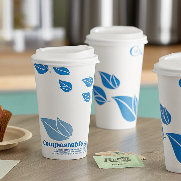 Three white EcoChoice paper hot cups with blue leaf print on a table.