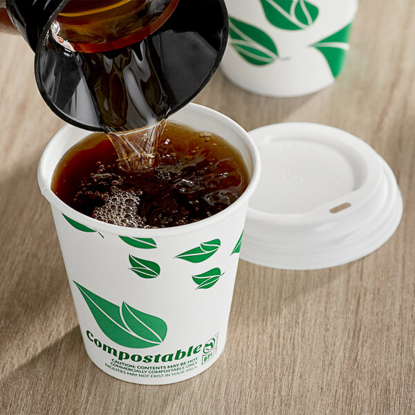 A leaf print EcoChoice paper hot cup filled with brown liquid on a counter.