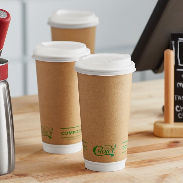 A couple of EcoChoice brown paper cups sitting on a table next to two cups of coffee.