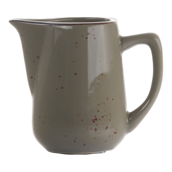 A gray and green speckled International Tableware creamer with a handle.