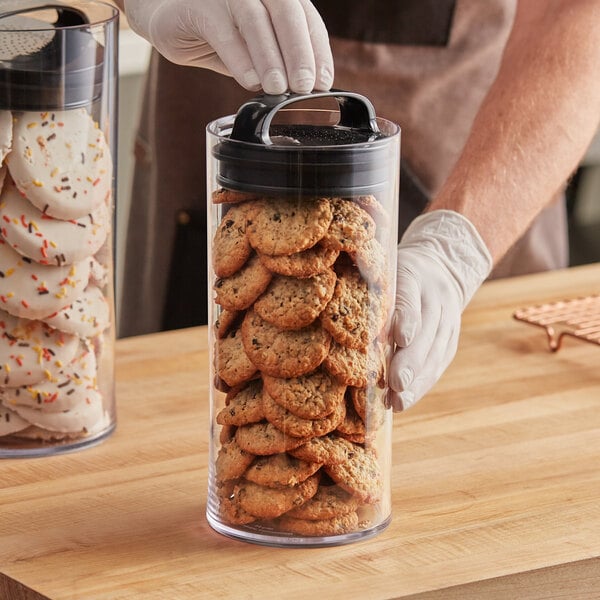 A hand holding a Prepara Evak Fresh Saver container filled with cookies.