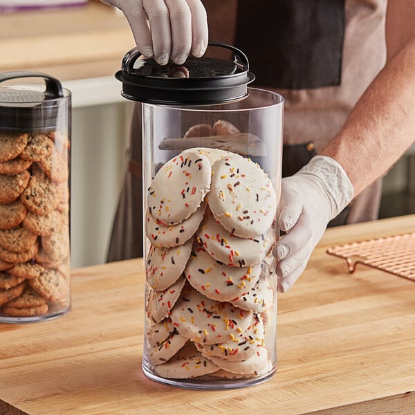 A person holding a Prepara Evak Fresh Saver airtight food storage container full of cookies.