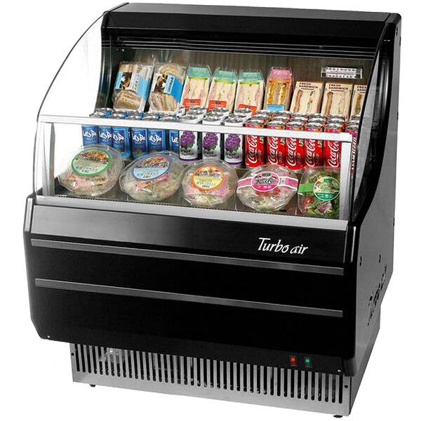 A black Turbo Air slim line horizontal air curtain display case with food in it.