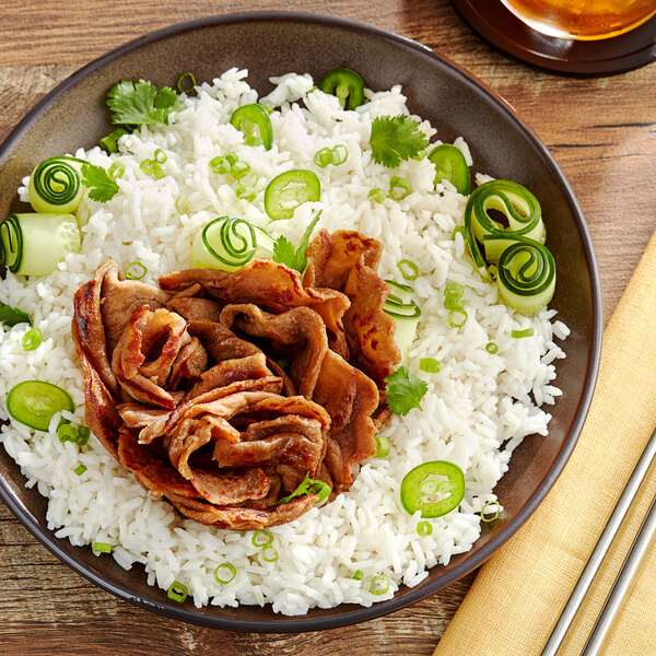 A plate of rice with UNLIMEAT plant-based sliced beef on a wood table.