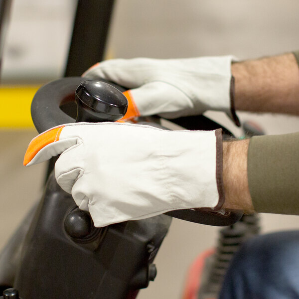 A person wearing Cordova Standard Grain Cowhide Leather gloves with Hi-Vis Orange Fingertips on a vehicle.