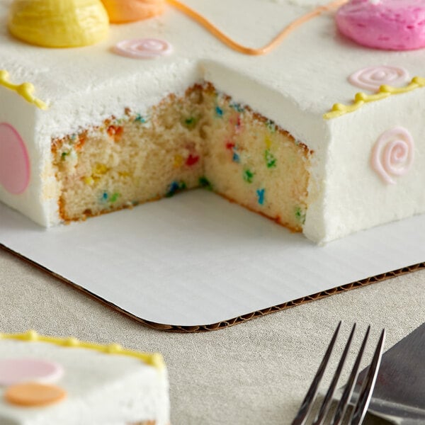 A cake with a slice missing on a white Baker's Mark quarter sheet cake pad.