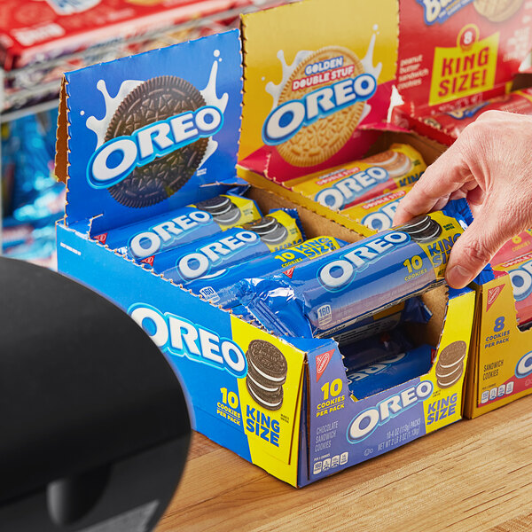 A hand reaching for a box of Nabisco Oreo cookies.