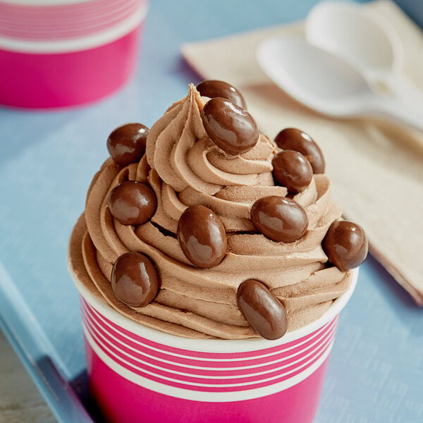 A cup of ice cream with chocolate covered peanuts.