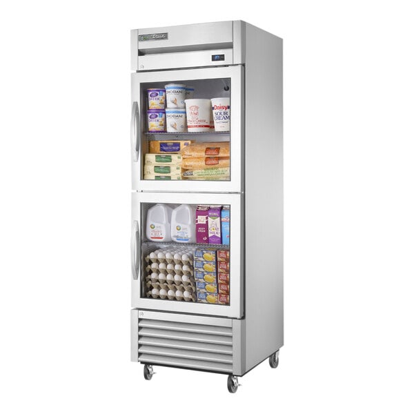 A True stainless steel reach-in refrigerator with glass half doors full of food.