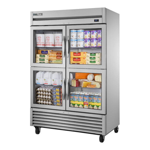 A True reach-in refrigerator with glass half doors filled with a variety of products.