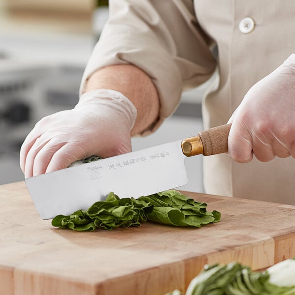A person using a Dexter-Russell Chinese Cleaver knife to cut vegetables on a cutting board.