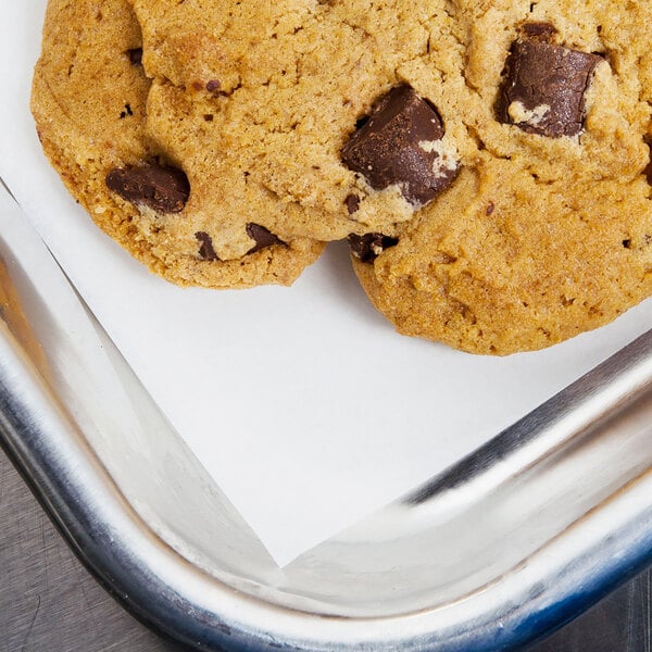 A Baker's Lane parchment paper lined tray with a chocolate chip cookie on it.