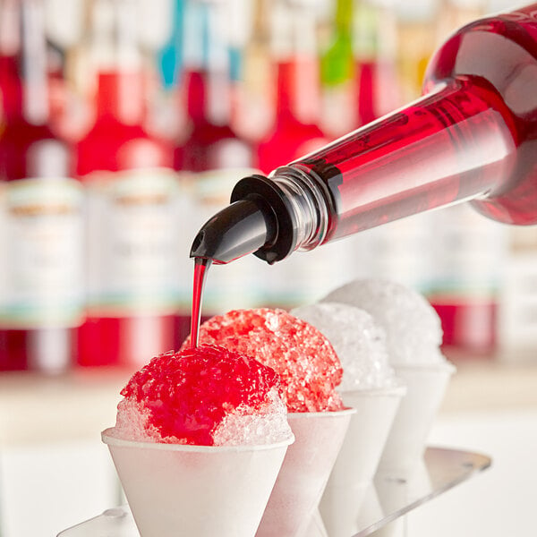A person pouring Hawaiian Shaved Ice Tiger's Blood syrup over a cup of shaved ice.