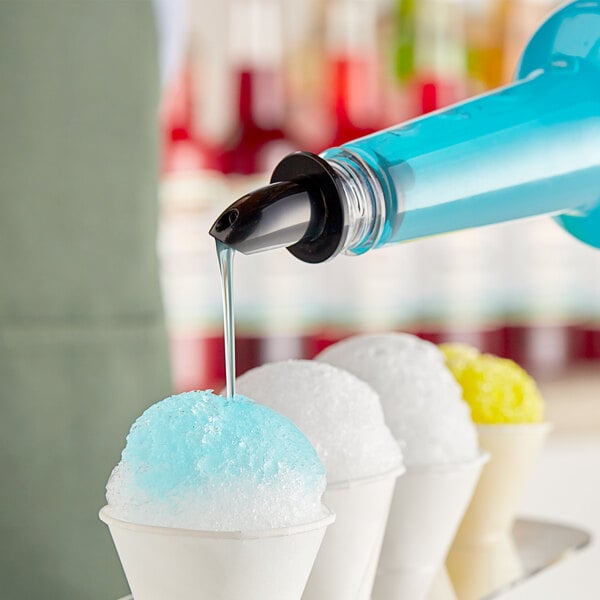 A person pouring Hawaiian Shaved Ice Blue Cotton Candy syrup onto a snow cone.