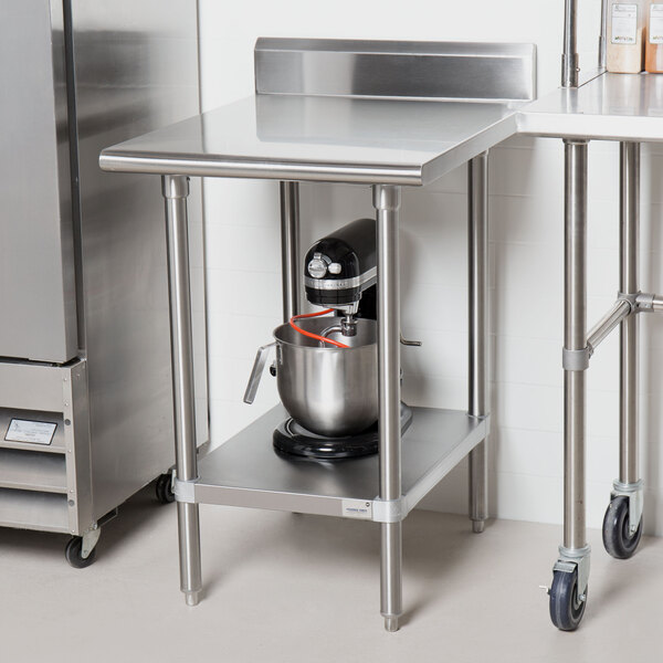 An Advance Tabco stainless steel work table with undershelf and a mixer on it.