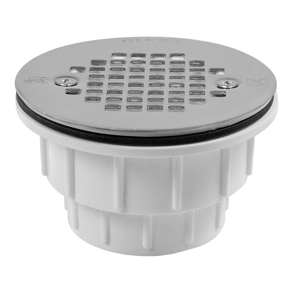 A white plastic Sioux Chief shower drain with a round hole and a silver lid.