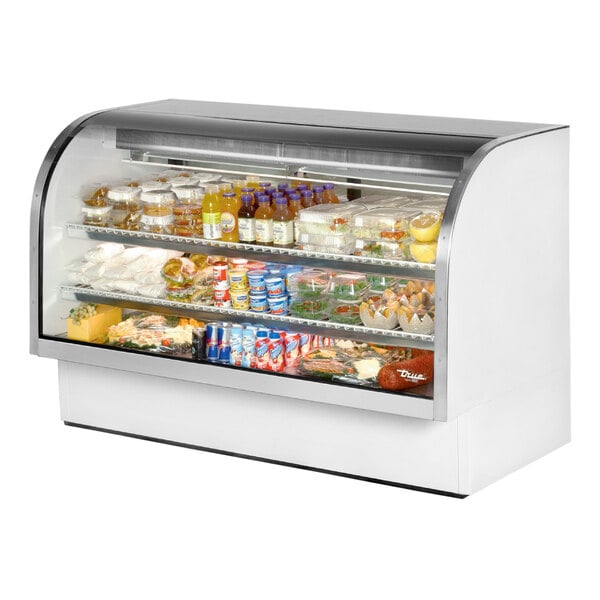 A True white curved glass refrigerated deli case with food on shelves.