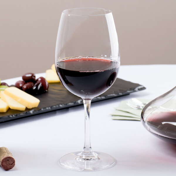 A Stolzle Weinland wine glass full of red wine next to a tray of cheese and grapes.