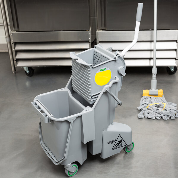 A grey Unger mop bucket with a side-press wringer on the floor.