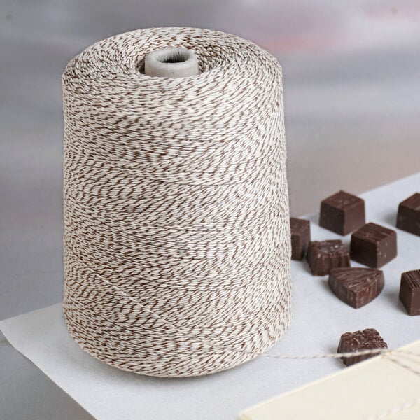 A Baker's Mark brown and white variegated twine cone next to chocolates.