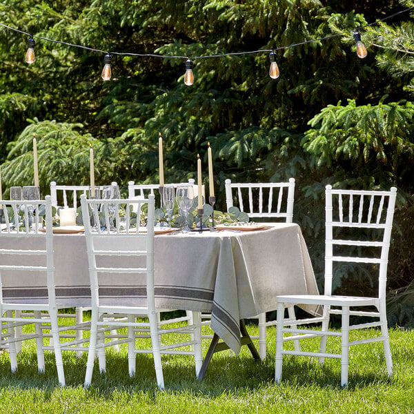 A table set with a Lancaster Table & Seating White Wood Chiavari Chair and a white tablecloth.