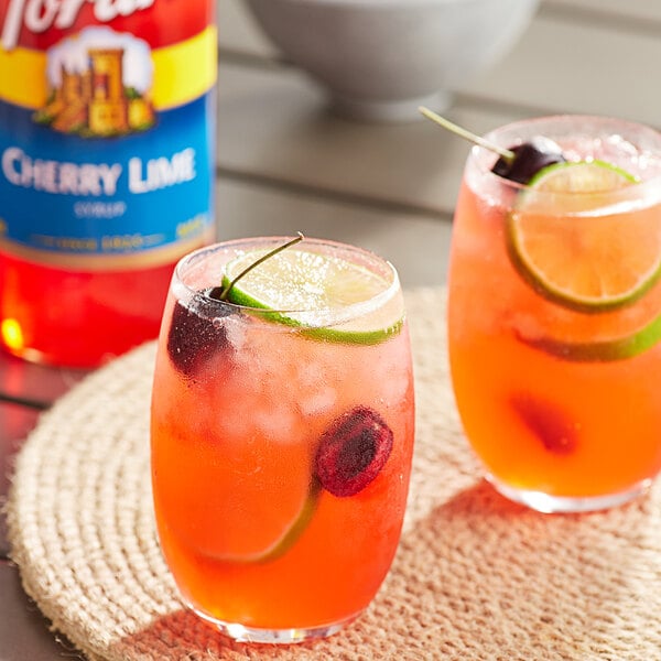 A pair of glasses of cherry limeade with Torani cherry lime syrup and fruit.