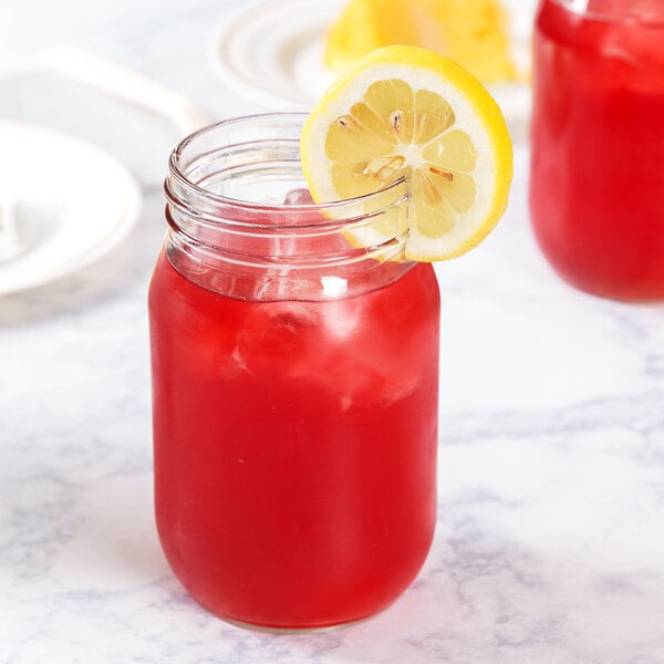 A Libbey mason jar filled with a red drink and a lemon slice.