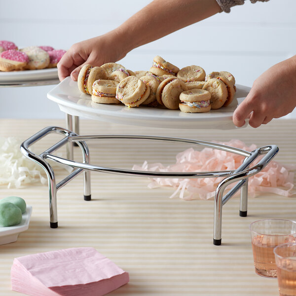 A plate of cookies displayed on a Vollrath display stand on a table.
