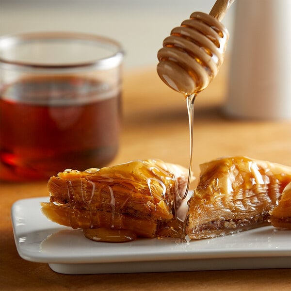 A piece of food with honey dripping from a honey dipper.