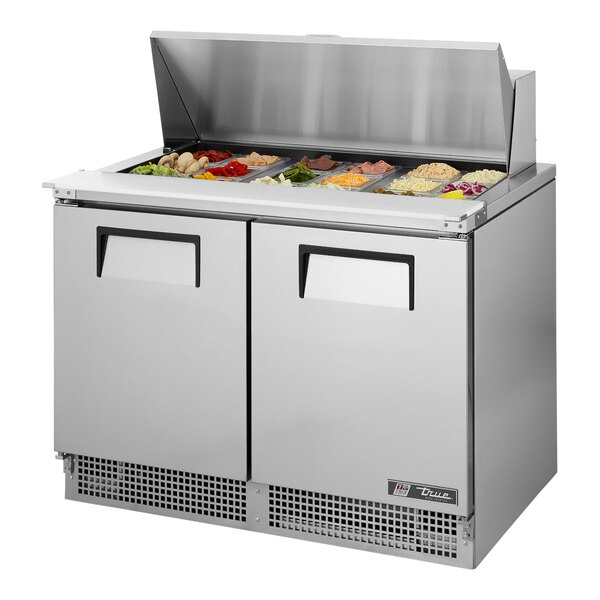 A True 2 door refrigerated sandwich prep table on a stainless steel counter.