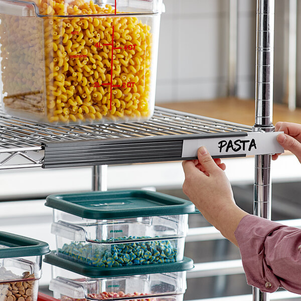 A plastic container of pasta labeled with a Regency gray label holder on a metal shelf.