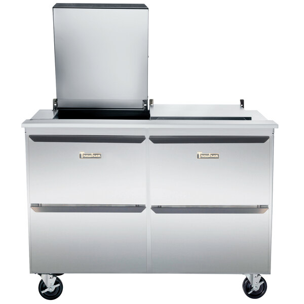 A Traulsen stainless steel refrigerator with 4 drawers on top of a stainless steel counter.
