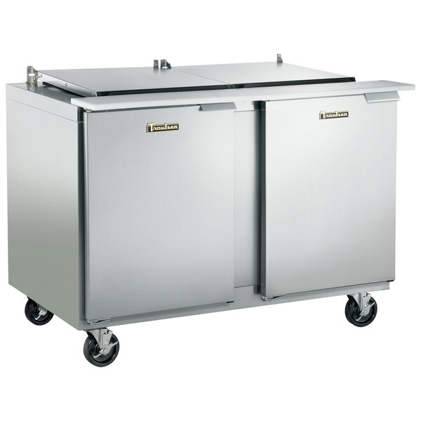 A large stainless steel Traulsen refrigerated prep table with two left hinged doors on wheels.