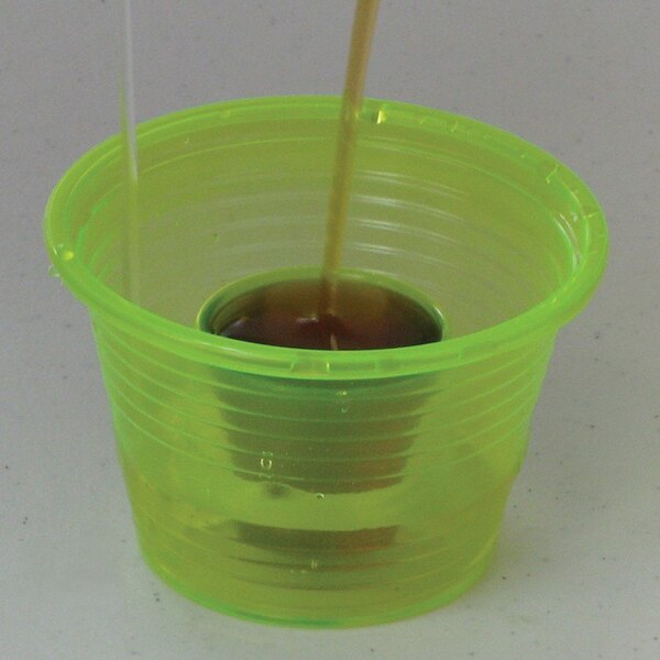 A green Disposabomb Power Bomb being poured into a green plastic cup with a straw.