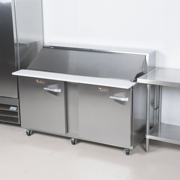 A large stainless steel Traulsen refrigerator with two left hinged doors and a white shelf inside.