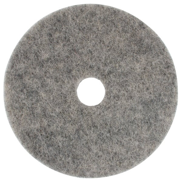 A grey circular Scrubble floor pad with a hole in the center.
