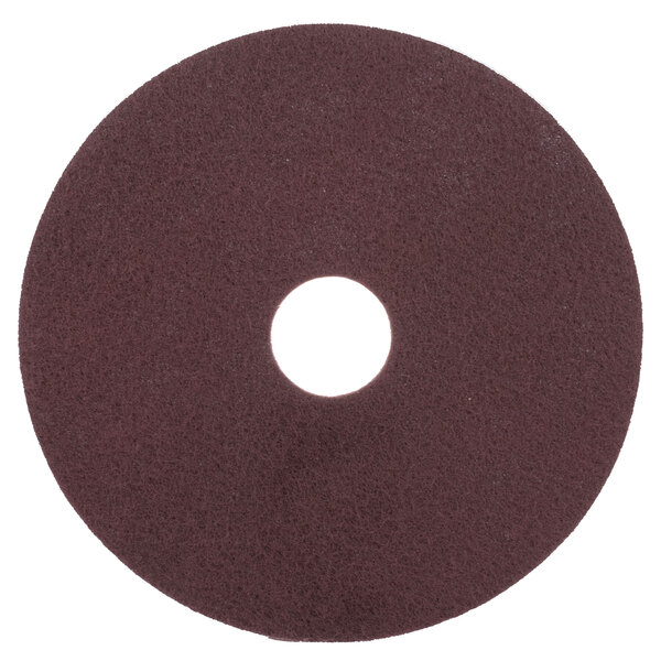 A brown circular Scrubble by ACS conditioning floor pad with a hole in the center.